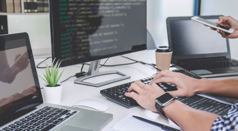 TOP Erros que você não deve cometer na Otimização de Conteúdo On page/SEO Homem trabalhando em um computador e notebook ao lado