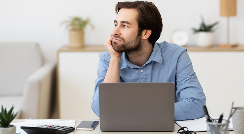 Como Ser Mais Produtivo no Trabalho? Veja dicas, métodos e muito mais! Homem branco procrastinando em frente a um notebook.