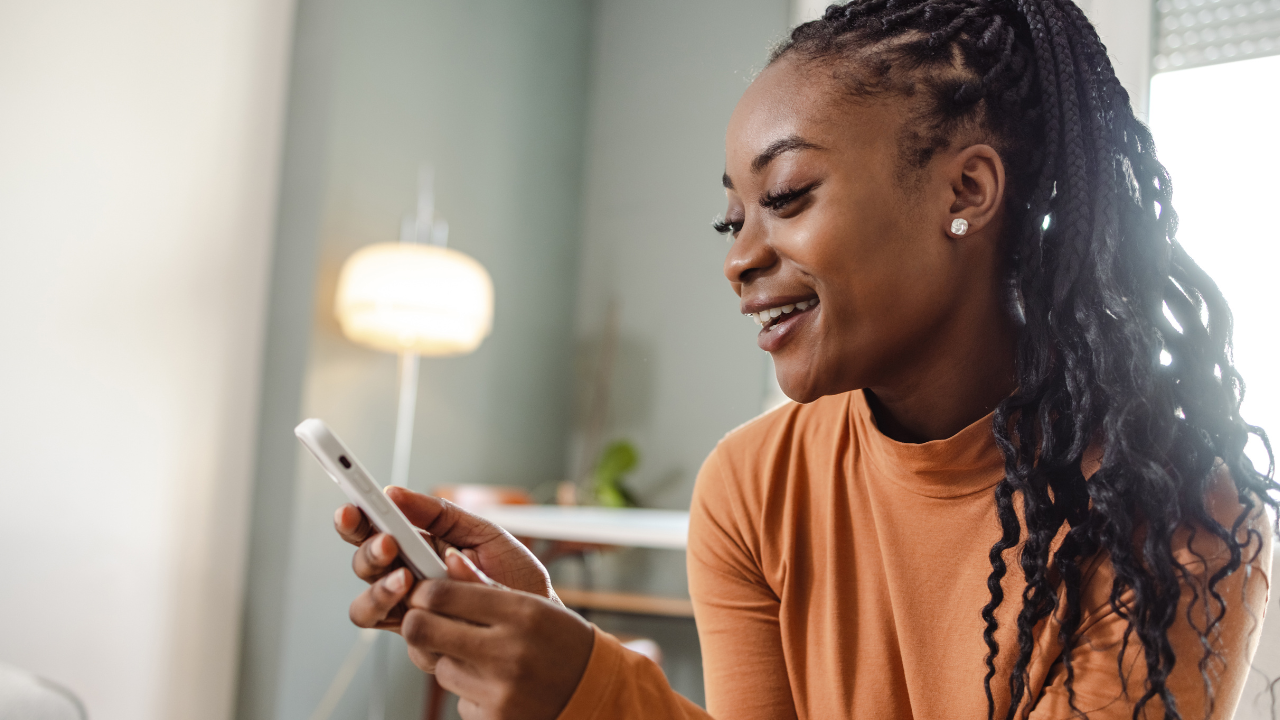 Cliente feliz mexendo no celular, remetendo a uma boa experiência de SEO.